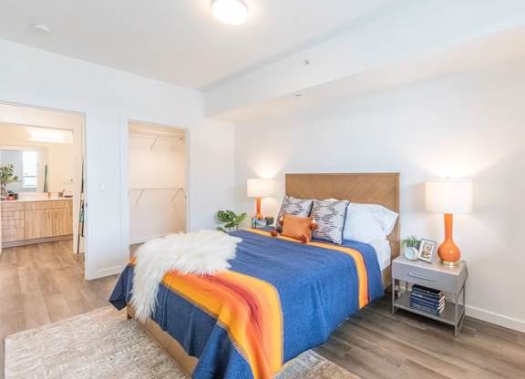 A bedroom with a bed covered in a blue and orange comforter.