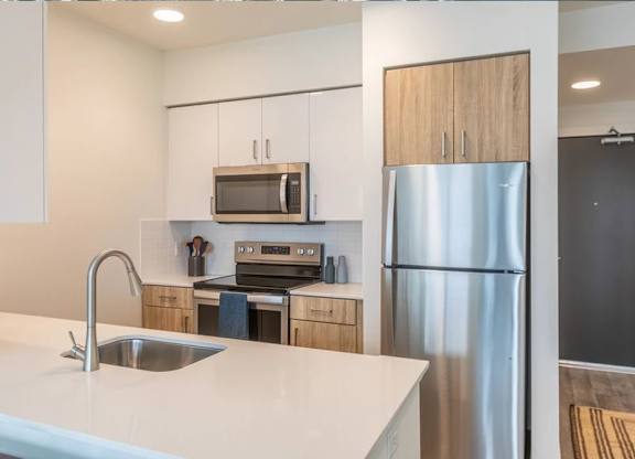 A modern kitchen with a stainless steel refrigerator and a white countertop.