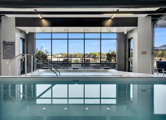 A large indoor swimming pool with a glass bottom and a view of the outdoors through the windows.