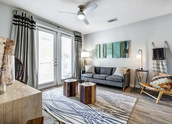 A living room with a grey couch, a wooden coffee table, and a striped rug.