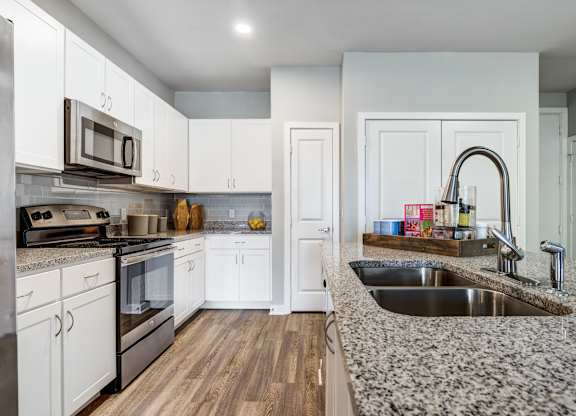 A kitchen with white cabinets and a granite countertop.