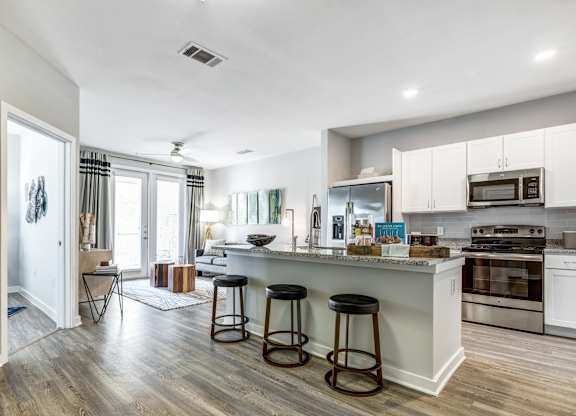 A kitchen with white cabinets and a wooden floor.