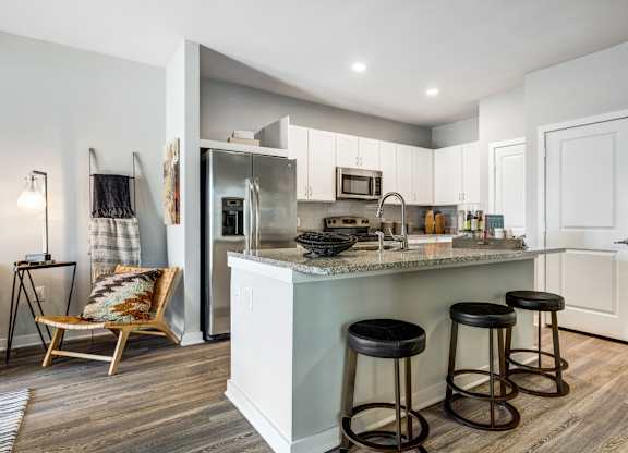 A kitchen with a bar stool in front of it.
