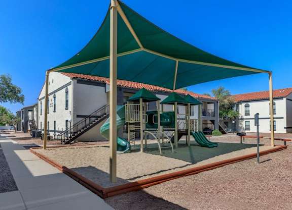 A playground with a green canopy and a slide.