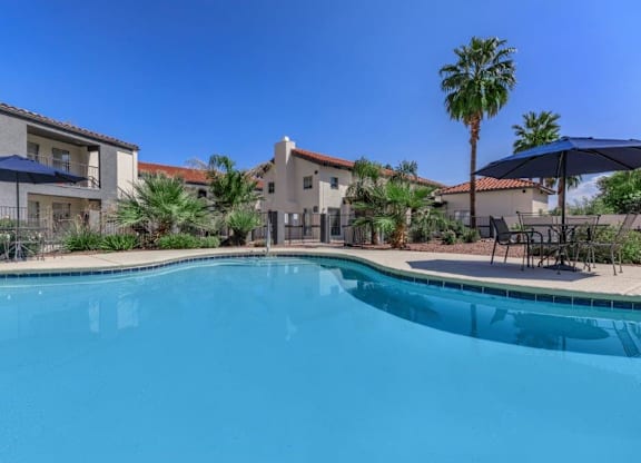 A swimming pool surrounded by palm trees and a building in the background.