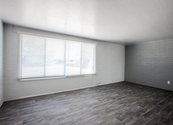 A room with a window and wooden flooring.