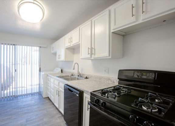 A kitchen with black stove and white cabinets.