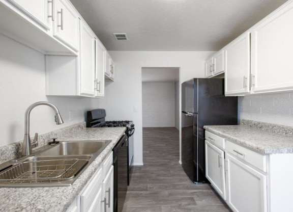 A kitchen with white cabinets and a granite countertop.