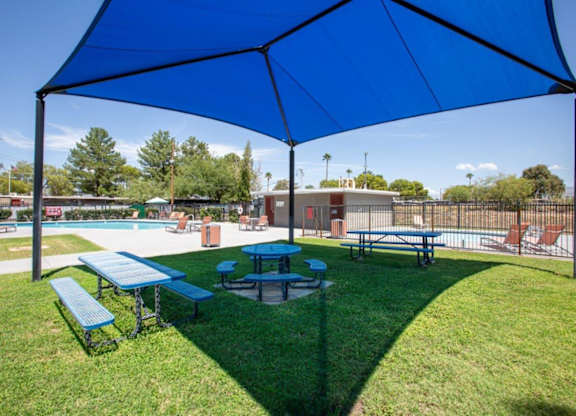 A blue canopy is over a picnic table and two benches.