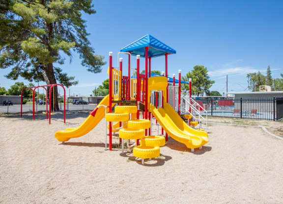A playground with a yellow slide and a blue canopy.