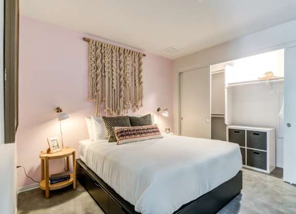 A bedroom with a bed, nightstand, and a window with curtains.