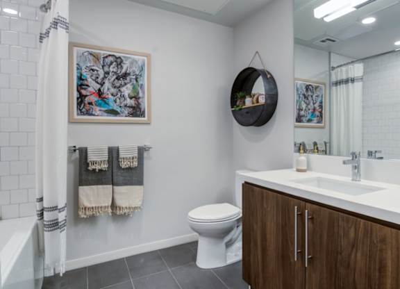A bathroom with a toilet, sink, and a mirror.