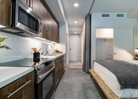 A modern kitchen with a bedroom in the back.