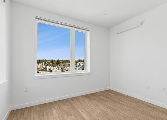 A room with a large window overlooking a town.