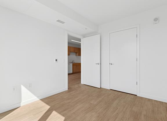 A white room with a wooden floor and two white doors.