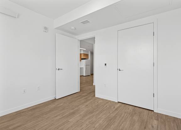 A hallway with white doors and wooden floors.