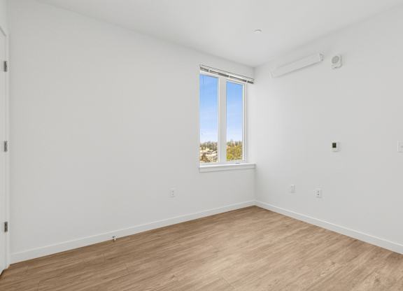 A room with a window and a wooden floor.