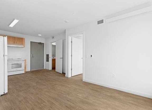A spacious room with a white wall and a wooden floor.