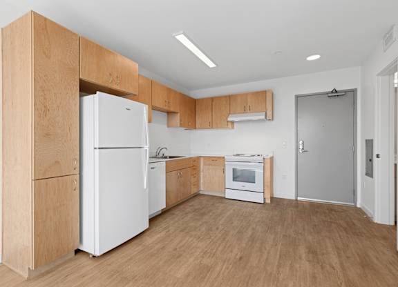 A kitchen with white appliances and wooden cabinets.