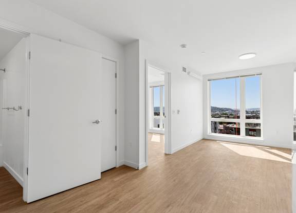A white room with a large window and wooden floors.