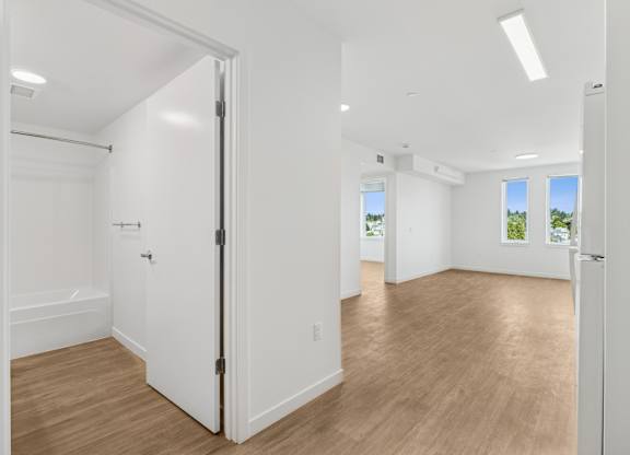 A white door is open to a room with wood flooring.
