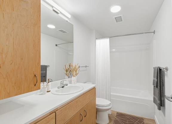 A white bathroom with a wooden cabinet and a white toilet.