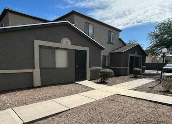 A modern house with a gravel driveway and a small tree.