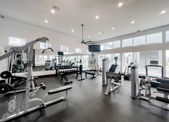 A spacious gym with a variety of equipment including a weight bench, a rowing machine, and a treadmill.