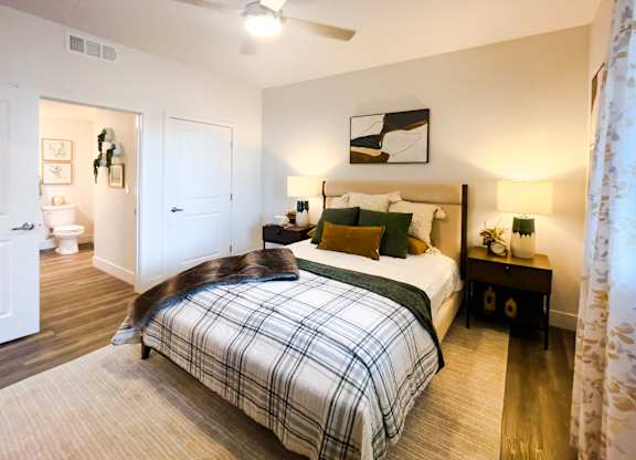 A bedroom with a bed, nightstand, and a ceiling fan.