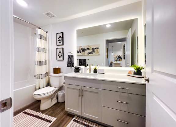 A bathroom with a toilet, sink, and mirror.
