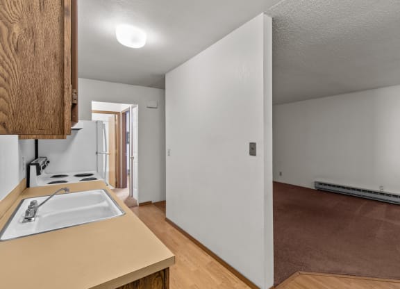the kitchen and living room of an empty house with white walls and wood floors
