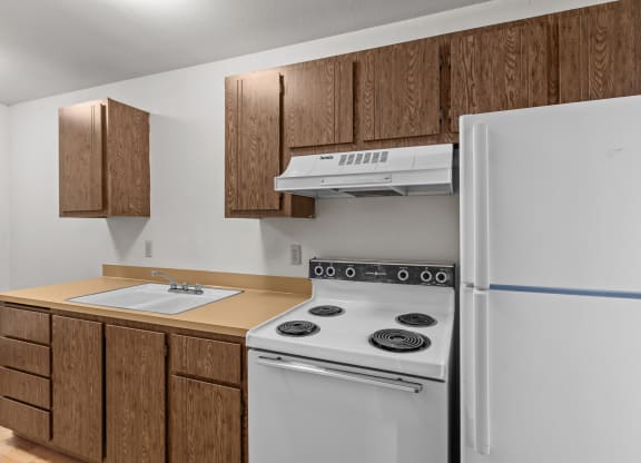 a kitchen with white appliances and wooden cabinets and a refrigerator