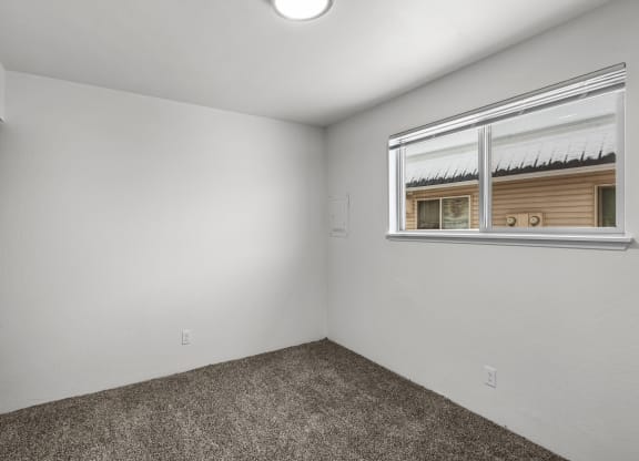 the living room of an empty home with a window and carpet