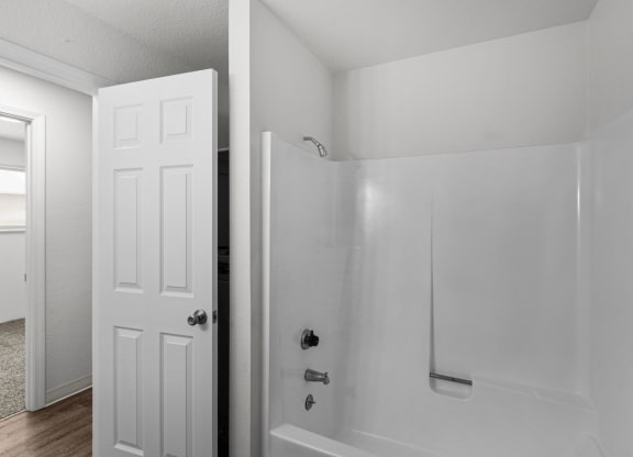an empty bathroom with a white shower and a white door