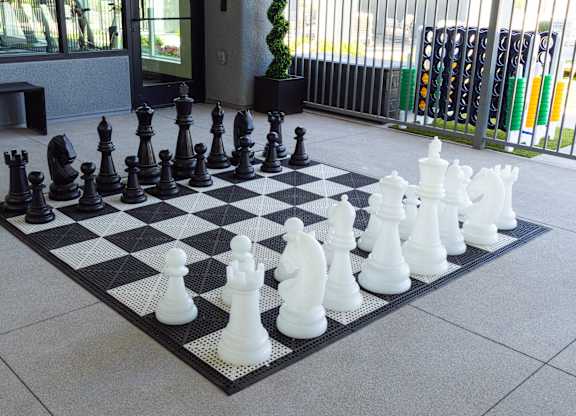 A giant chess set with black and white pieces on a black and white checkered board.