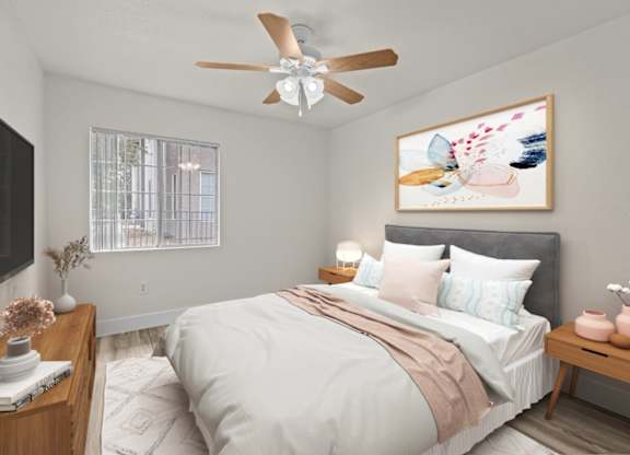 A bedroom with a bed, a ceiling fan, and a painting on the wall.