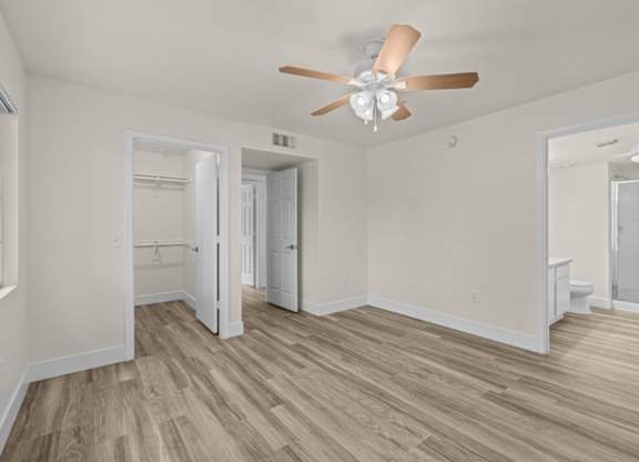 A room with a ceiling fan and wood flooring.