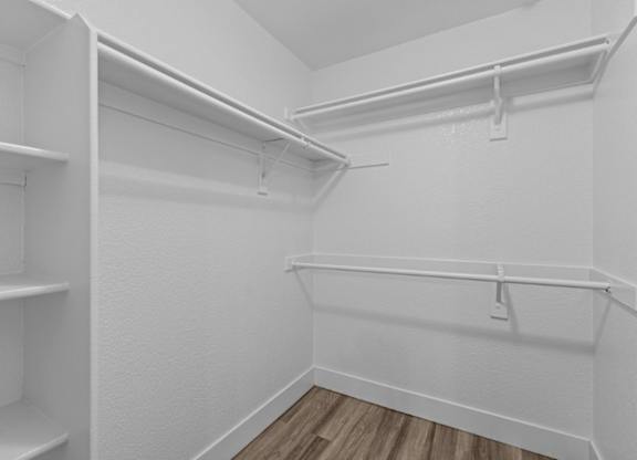 A white closet with shelves and a wooden floor.