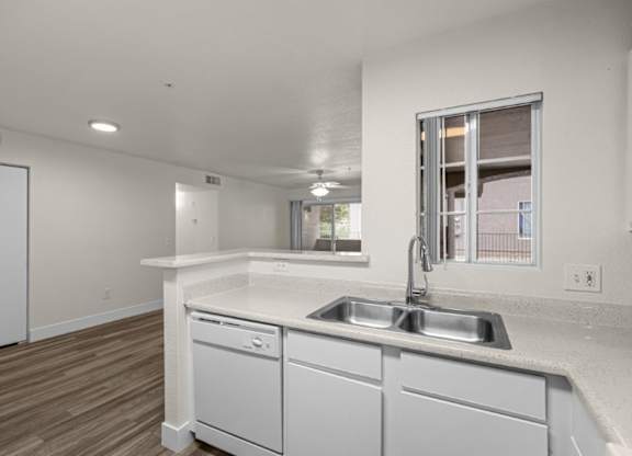 A kitchen with white cabinets and a window.