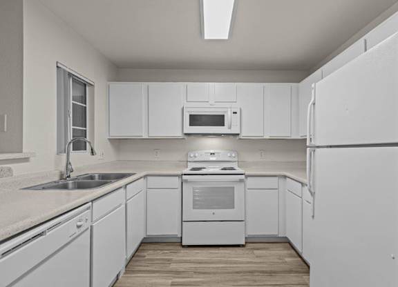 A white kitchen with a refrigerator, sink, and stove.