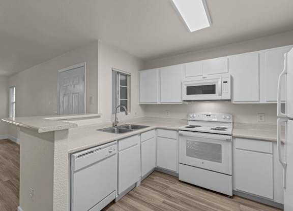 A white kitchen with wood flooring and white appliances.