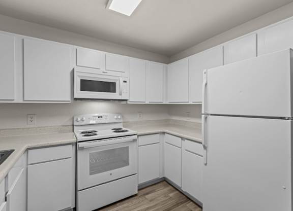 A white kitchen with a refrigerator, oven, and microwave.