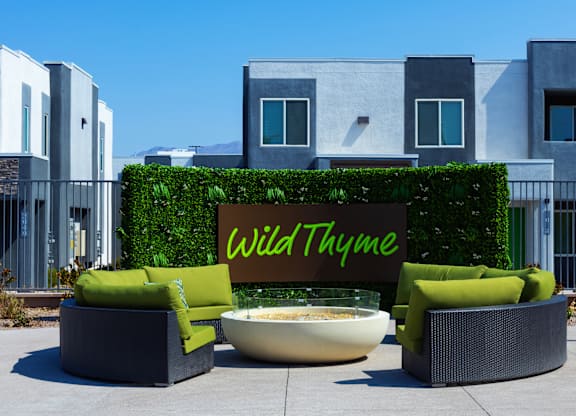 A sign that says Wild Thyme is in front of a green hedge.