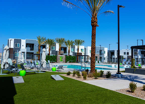 A palm tree stands in front of a row of houses with a pool in the foreground.
