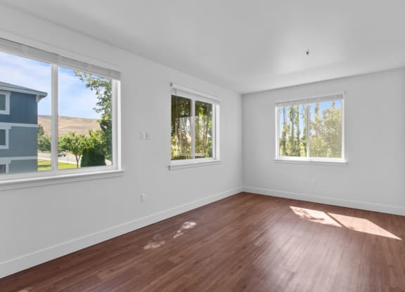 a bedroom with hardwood floors and three windows