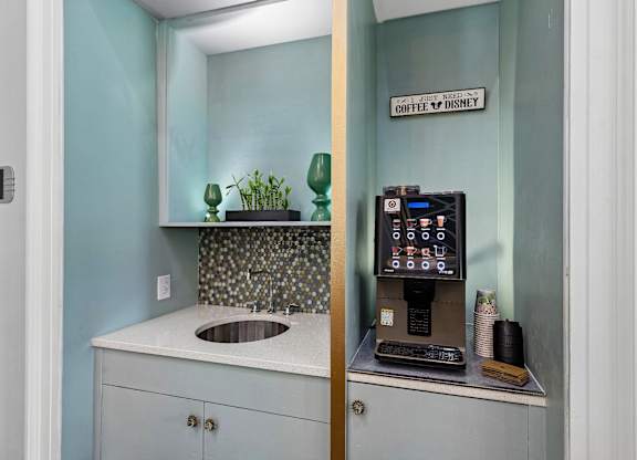 A small counter with a sink and a coffee machine.