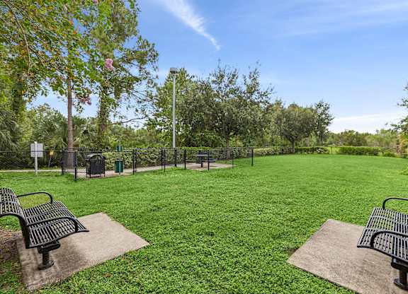 A park with two benches and a fence.