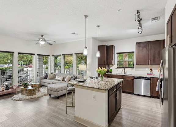 A modern kitchen with a large island and a living area with a couch and chairs.