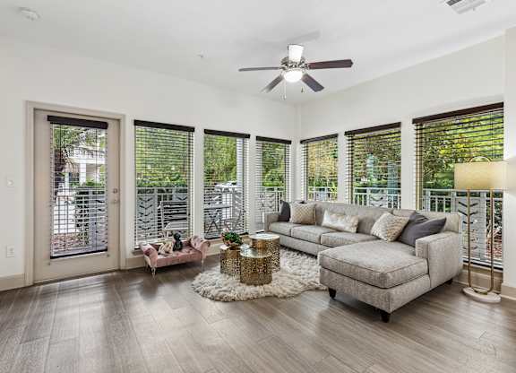 A living room with a grey couch, a coffee table, and a ceiling fan.