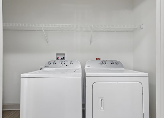 Two white front loading washing machines in a laundry room.